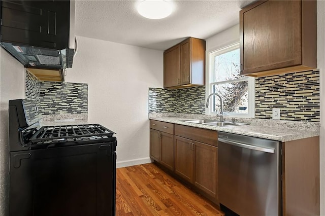 kitchen featuring dark wood-type flooring, sink, tasteful backsplash, black range with gas stovetop, and dishwasher