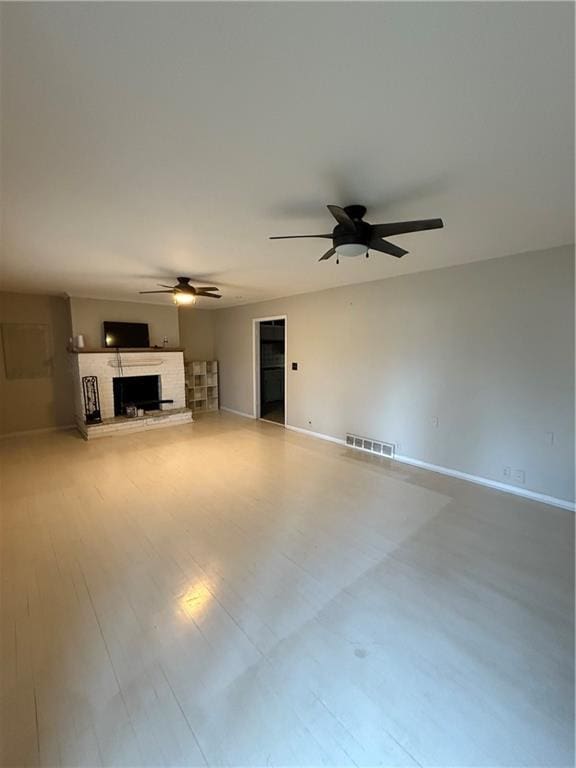 unfurnished living room featuring hardwood / wood-style flooring, a brick fireplace, and ceiling fan