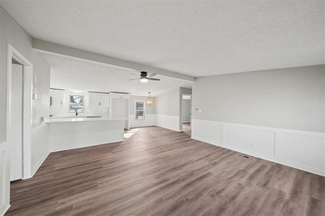 unfurnished living room featuring dark hardwood / wood-style flooring, ceiling fan, lofted ceiling with beams, and a textured ceiling