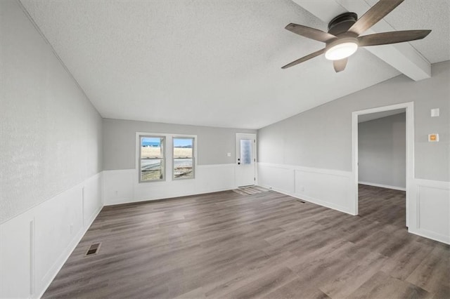 spare room with dark hardwood / wood-style flooring, vaulted ceiling with beams, a textured ceiling, and ceiling fan