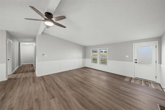 unfurnished living room with ceiling fan, lofted ceiling, dark wood-type flooring, and a textured ceiling