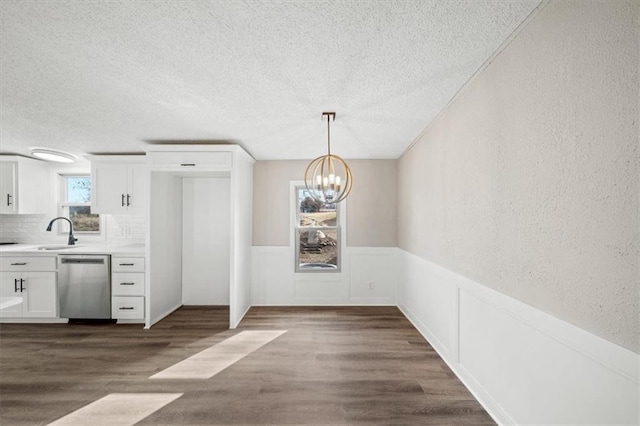 kitchen featuring white cabinetry, stainless steel dishwasher, dark wood-type flooring, and hanging light fixtures