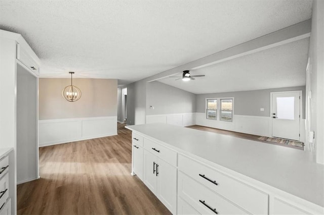 kitchen featuring decorative light fixtures, a textured ceiling, hardwood / wood-style floors, ceiling fan with notable chandelier, and white cabinets