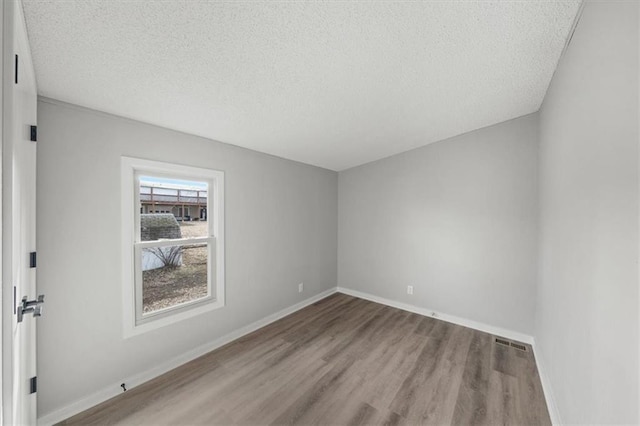 unfurnished room with light hardwood / wood-style floors and a textured ceiling