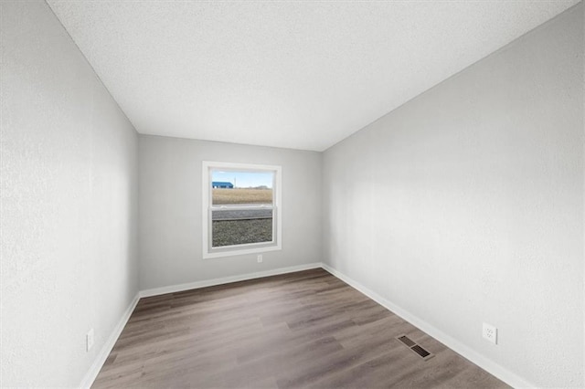 unfurnished room featuring hardwood / wood-style floors and a textured ceiling