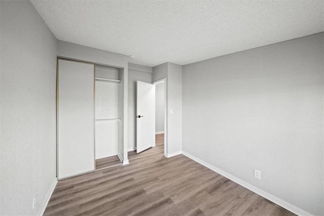 unfurnished bedroom featuring hardwood / wood-style floors, a closet, and a textured ceiling