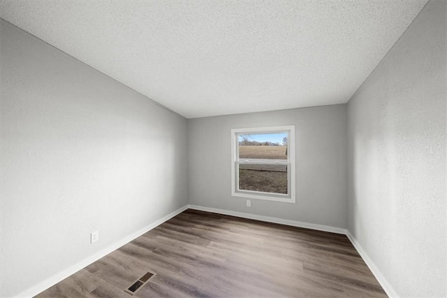 spare room featuring hardwood / wood-style flooring and a textured ceiling