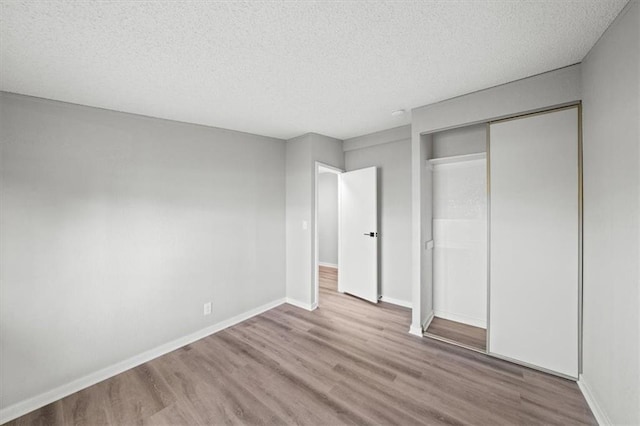 unfurnished bedroom featuring a textured ceiling, light wood-type flooring, and a closet