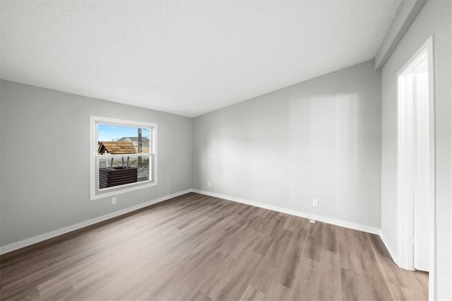 unfurnished room with light hardwood / wood-style flooring and a textured ceiling