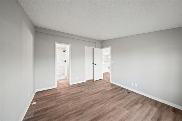 unfurnished room with hardwood / wood-style floors and a textured ceiling