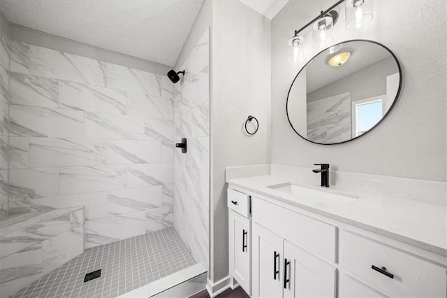 bathroom featuring vanity, a textured ceiling, and tiled shower