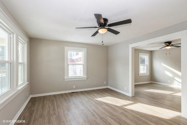 empty room featuring ceiling fan, plenty of natural light, and light hardwood / wood-style floors