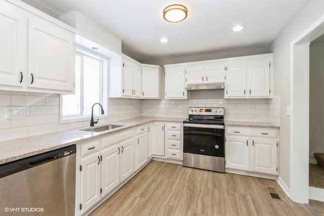 kitchen with white cabinetry, stainless steel appliances, light hardwood / wood-style flooring, light stone counters, and sink