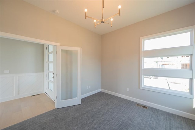 carpeted spare room featuring vaulted ceiling and a notable chandelier