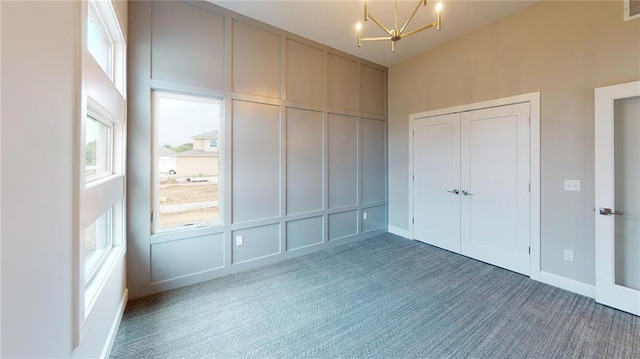 unfurnished bedroom with a closet, dark carpet, and a chandelier