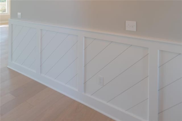 details featuring a wainscoted wall, a decorative wall, and wood finished floors