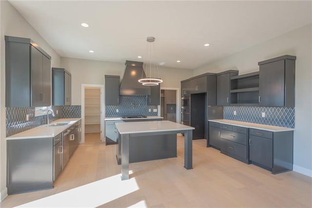 kitchen featuring light countertops, a kitchen island, decorative light fixtures, and custom exhaust hood