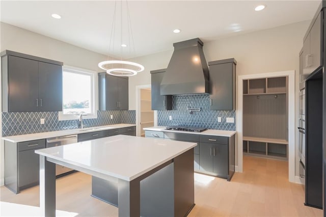 kitchen with light countertops, custom range hood, a kitchen island, black gas stovetop, and dishwasher