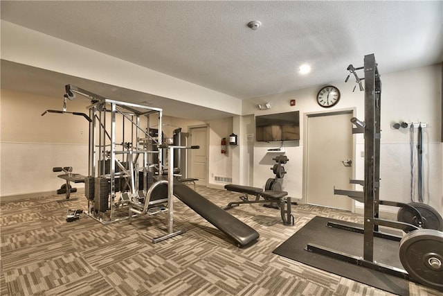 exercise room featuring a textured ceiling, carpet flooring, and visible vents