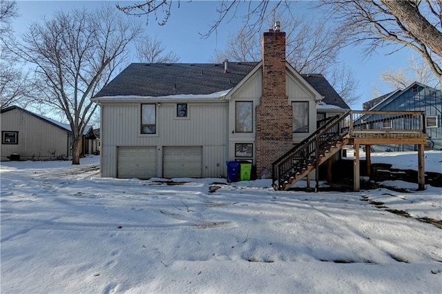 snow covered property featuring a deck and a garage