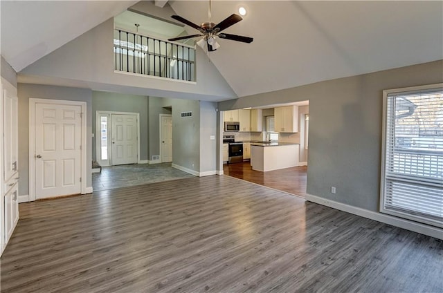 unfurnished living room with high vaulted ceiling, ceiling fan, and dark wood-type flooring