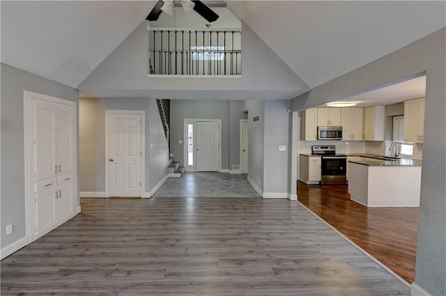 entryway featuring ceiling fan, a towering ceiling, wood-type flooring, and sink