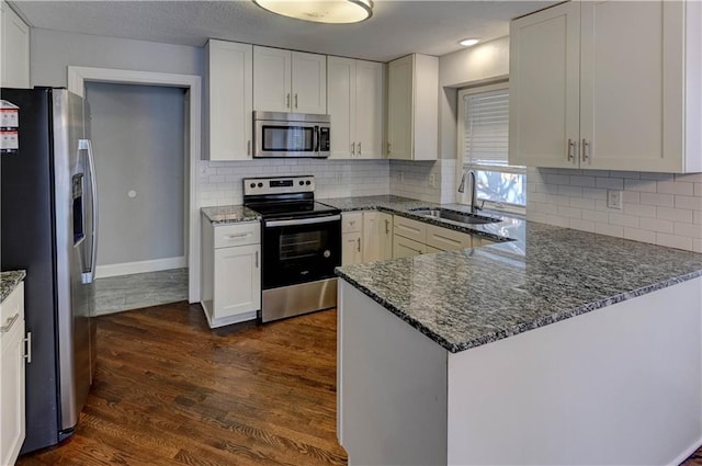 kitchen with sink, white cabinetry, appliances with stainless steel finishes, and kitchen peninsula