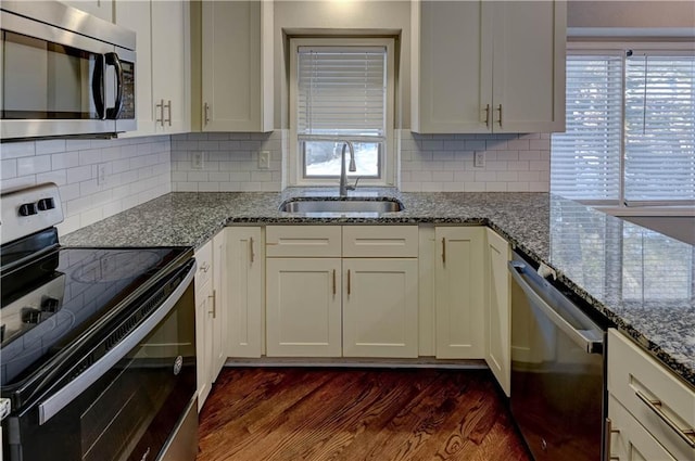 kitchen with backsplash, dark hardwood / wood-style floors, sink, stainless steel appliances, and light stone counters