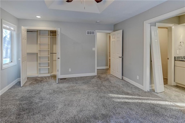 unfurnished bedroom with ceiling fan, light colored carpet, and a closet