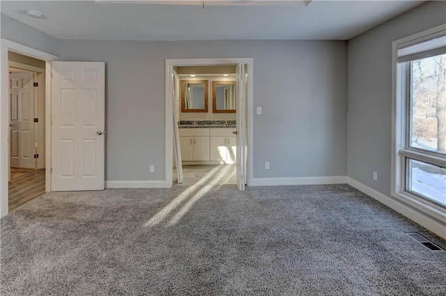 unfurnished bedroom featuring light carpet and ensuite bathroom