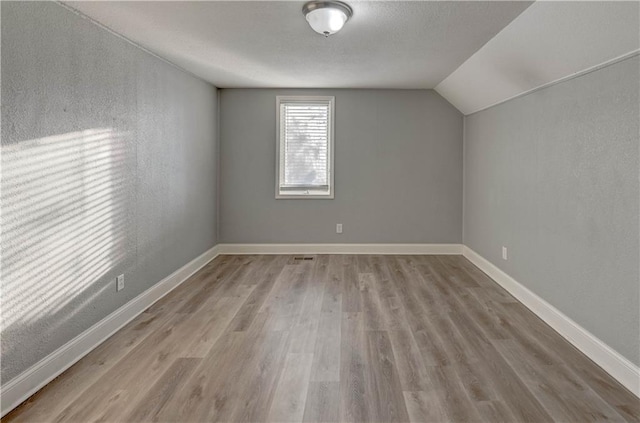 additional living space with lofted ceiling and light wood-type flooring