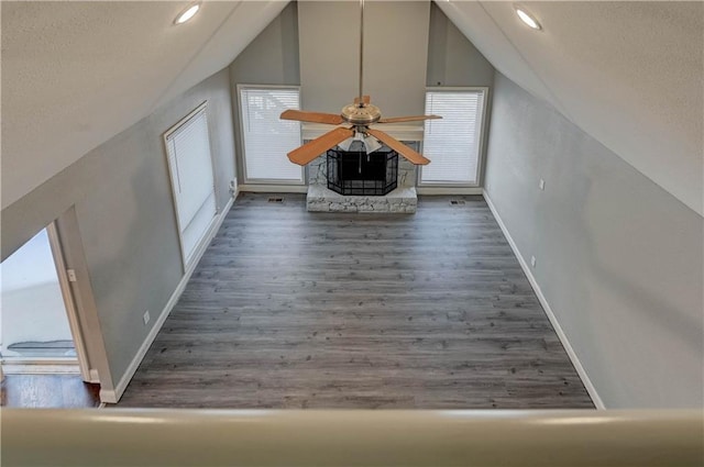 bonus room featuring lofted ceiling, dark hardwood / wood-style flooring, and a stone fireplace