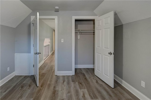 unfurnished bedroom featuring a closet, vaulted ceiling, and light hardwood / wood-style flooring