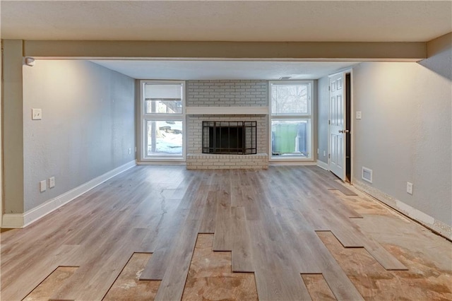 unfurnished living room featuring a brick fireplace and light wood-type flooring