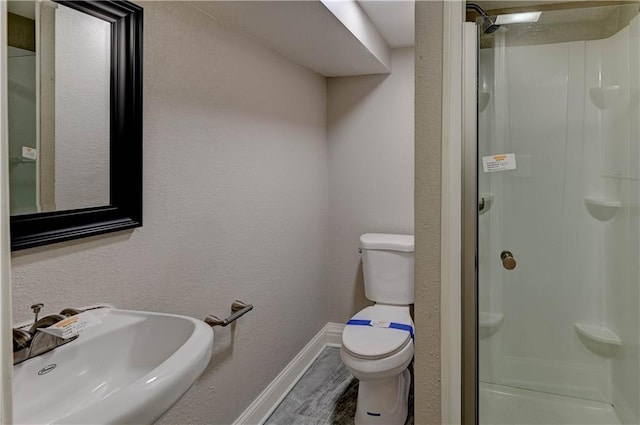 bathroom with toilet, walk in shower, and sink