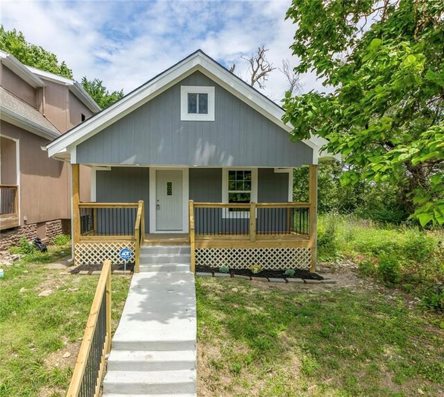 bungalow with covered porch and a front lawn