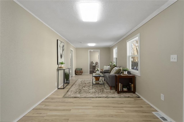 living room featuring a textured ceiling, ornamental molding, and light wood-type flooring