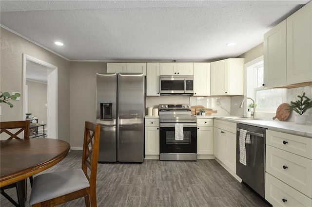 kitchen with a textured ceiling, appliances with stainless steel finishes, dark wood-type flooring, tasteful backsplash, and sink