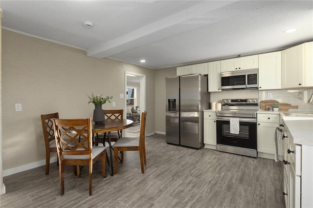 kitchen with appliances with stainless steel finishes, sink, white cabinets, hardwood / wood-style flooring, and a textured ceiling