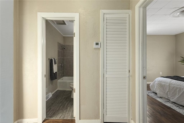 bathroom with hardwood / wood-style flooring, tiled shower / bath, and toilet