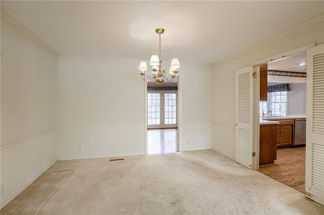 spare room featuring light colored carpet, crown molding, and a notable chandelier