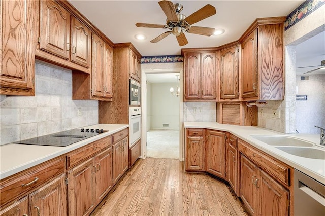 kitchen featuring ceiling fan with notable chandelier, stainless steel appliances, light hardwood / wood-style floors, and sink