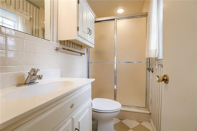 bathroom featuring toilet, a shower with door, decorative backsplash, tile walls, and vanity