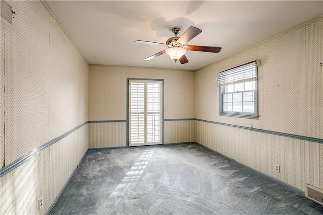 empty room featuring ceiling fan and dark colored carpet