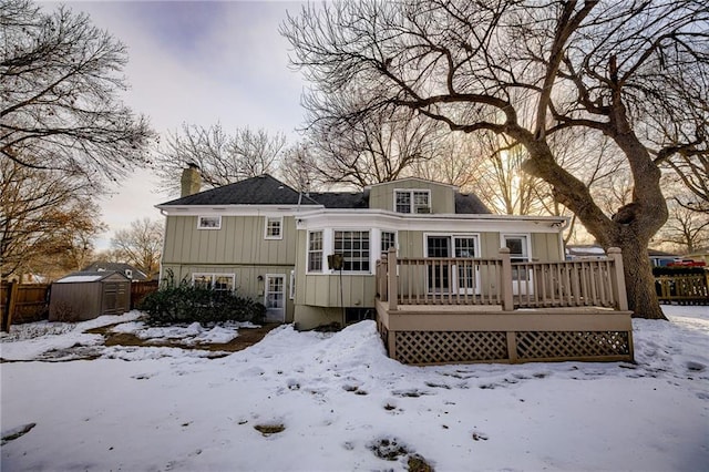 snow covered property with a storage shed and a deck