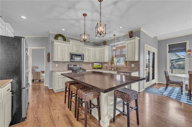 kitchen with light hardwood / wood-style flooring, sink, backsplash, appliances with stainless steel finishes, and pendant lighting