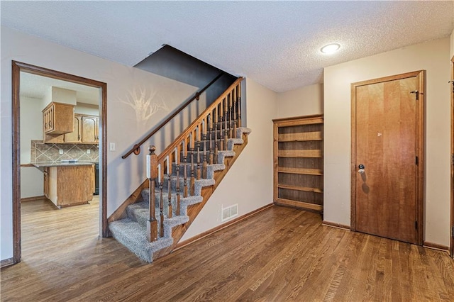 stairs featuring wood-type flooring and a textured ceiling