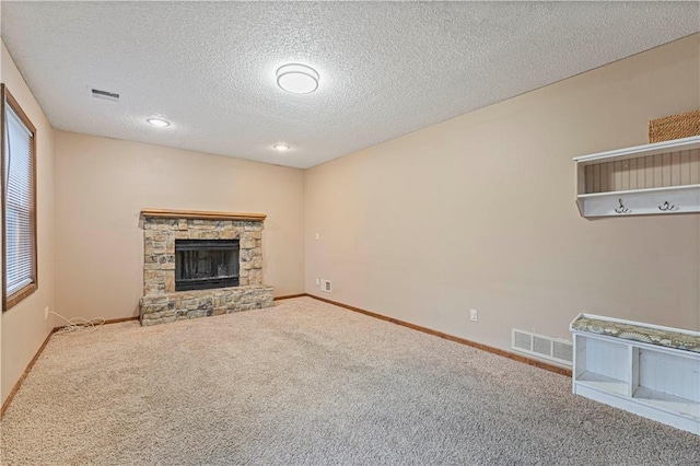 unfurnished living room featuring a stone fireplace, a textured ceiling, and carpet