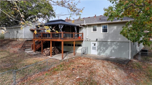 back of property featuring a garage, a gazebo, and a deck