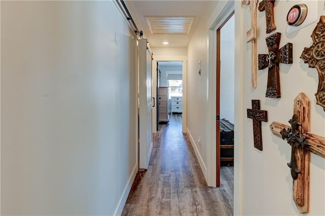 hallway featuring wood-type flooring and a barn door